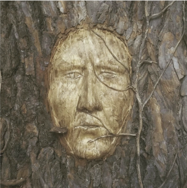 Gesicht in Baumrinde geschnitzt